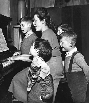 Family and cat practising Christmas carols at the piano Family and cat practising Christmas carols at the piano