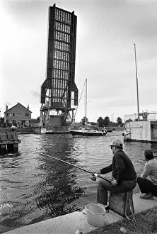 Fishermen on towpath as yacht passes raised Pegasus Bridge Fishermen on towpath as yacht passes raised Pegasus Bridge
