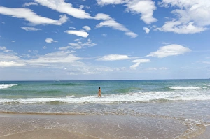 A girl baths and watches a passing boat on a beach A girl baths and watches a passing boat on a beach