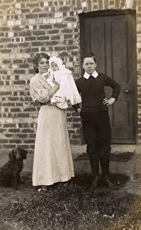 Girl and boy with baby and spaniel outside a house
