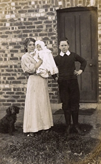 Girl and boy with baby and spaniel outside a house Girl and boy with baby and spaniel outside a house
