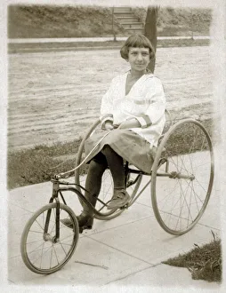 Peddle Gallery: Girl riding a vintage peddle tricycle along the sidewalk