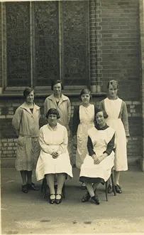 Group of six women, wearing aprons or overalls. They look as if they are staff at a Group of six women, wearing aprons or overalls. They look as if they are staff at a