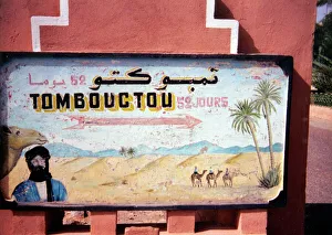 A hand-painted sign showing the time it would take to reach Timbuktu in Mali (52 days A hand-painted sign showing the time it would take to reach Timbuktu in Mali (52 days