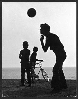 <b class=qtipBold><figcaption>Header Silhouette</figcaption></b><br>Silhouette of a teenager heading a football on a beach, watched by two smaller boys, one holding his bicycle.<br><em>© Mary Evans Picture Library/TONY BOXALL</em> Header Silhouette