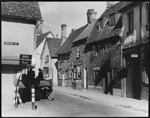 Prints of The corner of Bridge Street, Hitchin, Hertfordshire, where the speed limit for W.D. (War Department) vehicles is 15 m.p.h. A horse and cart keeps strictly to this limit Hertfordshire Prints: Hitchin, Herts 1940s Print: Bridge Street Scene with Horse and Cart