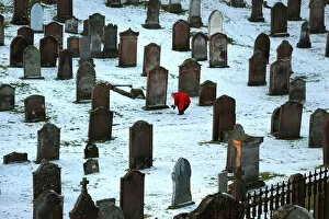 Lady in red coat lays bouquet on a grave, Kirkcudbright
