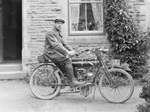 Man on an early motorcycle in front of a house Man on an early motorcycle in front of a house
