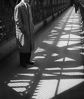 Man standing on bridge in light and shade Man standing on bridge in light and shade