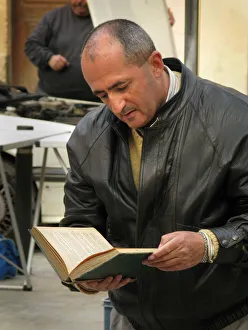 A middle-aged man reads a book near a bookstall in Palma A middle-aged man reads a book near a bookstall in Palma