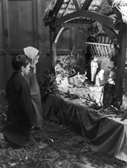 <b class=qtipBold><figcaption>Nativity Crib</figcaption></b><br>Two children kneel down to admire a traditional Christmas Nativity Crib, with models of Joseph, Mary and baby Jesus.<br><em>© Mary Evans Picture Library</em> Nativity Crib