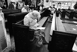 An old lady sits in a pew in Bath Abbey An old lady sits in a pew in Bath Abbey