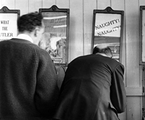 <b class=qtipBold><figcaption>Peepshows at Brighton</figcaption></b><br>Two men looking at peepshows of the What the Butler Saw variety in Brighton; one machine is advertised as 'Naughty! Naughty!' Date: 1950s<br><em>© Mary Evans Picture Library/HENRY GRANT</em> Peepshows at Brighton