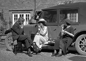 Three people picnicking at the side of a car Three people picnicking at the side of a car