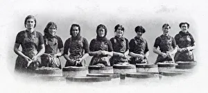 Photograph showing a group of Scottish women standing over the barrels that are being Photograph showing a group of Scottish women standing over the barrels that are being