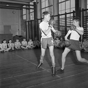 <b class=qtipBold><figcaption>Physical education, Boxing</figcaption></b><br>At a secondary school in Stoke on Trent, England, two boys box in front of their class mates, part of their physical education.<br><em>© Mary Evans Picture Library/HENRY GRANT</em> Physical education, Boxing