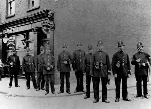 Prints of A group of perfectly turned-out police officers line up outside a barbers shop in London. Date: late 19th century Police Prints: Late 19th Century London Police Officers Print