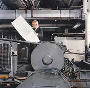 A large print proof is checked by a printer
