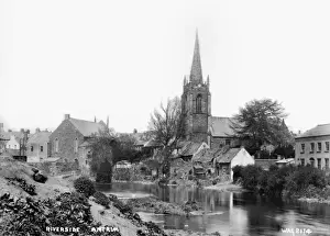 Prints of Riverside Antrim - a view of buildings including a Church with the river in the foreground. (Location: Northern Ireland: County Antrim: Antrim). Date: circa early 1900s River Prints: Early 20th Century Print of Antrim Riverside Scene