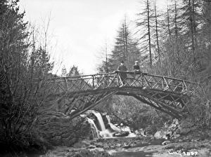 A rustic wooden bridge over a river and two men on it (unsha A rustic wooden bridge over a river and two men on it (unsha