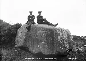 Prints of Samsons Stone, Downpatrick - a view of a large stone with two men sitting on top of it. (Location: Northern Ireland; County Down; Downpatrick). Date: circa early 1900s Down Prints: Early 20th Century Print of Samsons Stone, Downpatrick