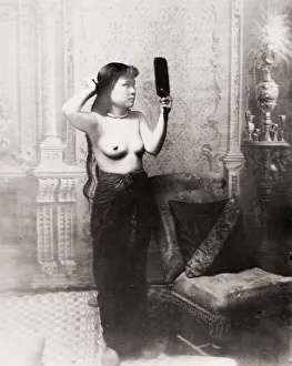 SE Asia, bare-breasted young woman doing her hair SE Asia, bare-breasted young woman doing her hair