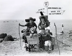 Signpost at Land's End, Cornwall, with charity walkers Signpost at Land's End, Cornwall, with charity walkers