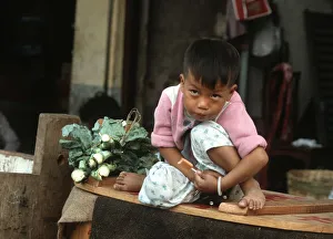 A small boy sits on his mothers vegetable stall, Hong Kong A small boy sits on his mothers vegetable stall, Hong Kong