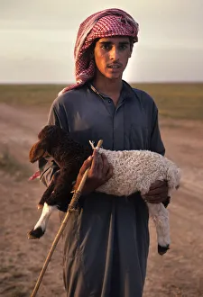 Syrian bedhouin shepherd boy holds a small lamb in his arms Syrian bedhouin shepherd boy holds a small lamb in his arms