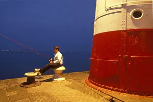 Teenage boy sits on a bollard while fishing, Newlyn Harbour Teenage boy sits on a bollard while fishing, Newlyn Harbour