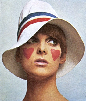 <b class=qtipBold><figcaption>White gangster hat by Edward Mann</figcaption></b><br>Model wearing a white gabardine "gangster" hat with red, white and blue striped band by Edward Mann. Worn with make-up by Richard Hudnut using bright pink bloom cream rouge for the hearts on the model's cheeks. Date: 1966<br><em>© Illustrated London News Ltd/Mary Evans</em> White gangster hat by Edward Mann