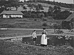 Woman and boy standing by a duckpond Woman and boy standing by a duckpond