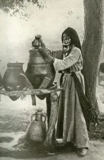 Woman in face veil drawing water from a jar, Egypt Woman in face veil drawing water from a jar, Egypt