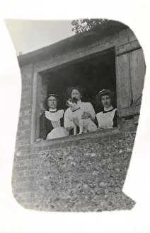 Three women with a dog at an open window Three women with a dog at an open window