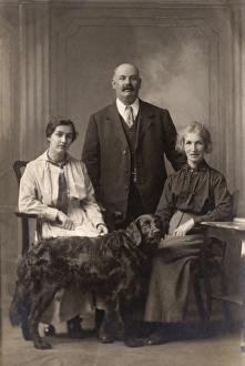 Two women and a man with a Flat-Coated Retriever Two women and a man with a Flat-Coated Retriever