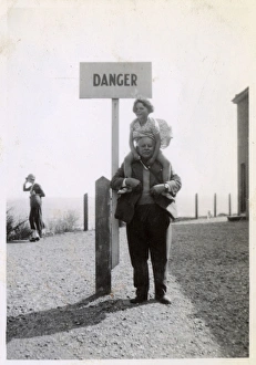 Young girl on Grandfathers shoulders by Danger sign Young girl on Grandfathers shoulders by Danger sign