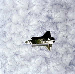 <b class=qtipBold><figcaption>Challenger as seen from SPAS</figcaption></b><br>Full view of Space Shuttle Orbiter Challenger in space, taken by the Space Pallet Satellite (SPAS). A heavily cloud-covered portion of the earth forms the backdrop for this scene of Challenger. Visible in the payload bay are the protective cradles for the Palapa-B and Telesat F communications satellites, the pallet for the NASA Office of Space and Terrestrial Applications (OSTA-2), the Remote Manipulator System (RMS) robot arm in the shape of the numeral seven and the KU- band antenna. A number of GetAway Special (GAS) canisters are also visible along the port side.<br><em>© NASA</em> Challenger as seen from SPAS