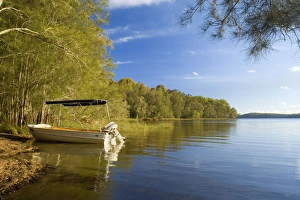 Boating idyll - small motorboat anchors in a tranquil bay at the Myall Lakes Boating idyll - small motorboat anchors in a tranquil bay at the Myall Lakes
