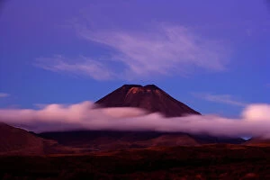 Mount Ngauruhoe - peak of perfectly shaped volcanoe Mt Ngauruhoe sticking out of clouds at dusk