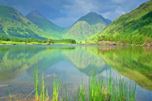 Mountain Scenery - reflection of Buachaille Etive Beag and Mor in lake during springtime with Rhododendron ponticum
