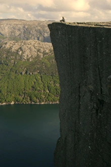 Preikestolen - person meditating near the edge of rock pulpit Preikestolen with vertical Preikestolen - person meditating near the edge of rock pulpit Preikestolen with vertical
