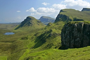 The Quiraing landscape - lake and rolling velvet green slopes sprinkled with basaltic The Quiraing landscape - lake and rolling velvet green slopes sprinkled with basaltic