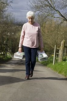 Recycling - woman carrying bundles of magazines