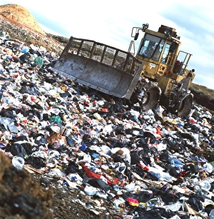 View of a bulldozer working a landfill refuse site View of a bulldozer working a landfill refuse site