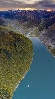 Aerial panoramic of sunset over Livigno and larch trees along the lake in autumn Aerial panoramic of sunset over Livigno and larch trees along the lake in autumn
