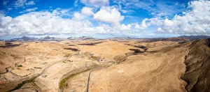 Aerial view of desert landscape and mountains crossed by asphalt road, Tefia Aerial view of desert landscape and mountains crossed by asphalt road, Tefia