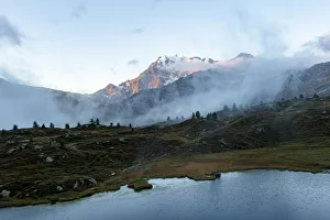 Aerial view of Fletschhorn and Galehorn mountains in fog at dawn from Hopschusee lake Aerial view of Fletschhorn and Galehorn mountains in fog at dawn from Hopschusee lake
