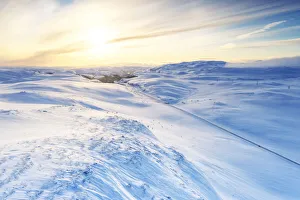 Aerial view of empty road across mountains covered with snow lit by sunrise, Sennalandet Aerial view of empty road across mountains covered with snow lit by sunrise, Sennalandet