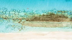Aerial view of woman floating on the crystal sea in between coral reef and white sand beach, Antigua, West Indies Aerial view of woman floating on the crystal sea in between coral reef and white sand beach, Antigua, West Indies
