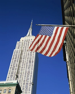 The American flag, the stars and stripes in front of the Empire State Building in New York The American flag, the stars and stripes in front of the Empire State Building in New York